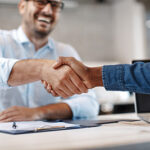 Business owner shaking hands with SEO Ocean County professional over a desk witha clipboard and laptop