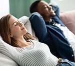 Couple relaxing on a couch after Monmouth County air conditioner repair