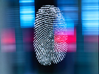 White thumbprint over a blurry blue and red background; Biometrics are part of the future of ITM service